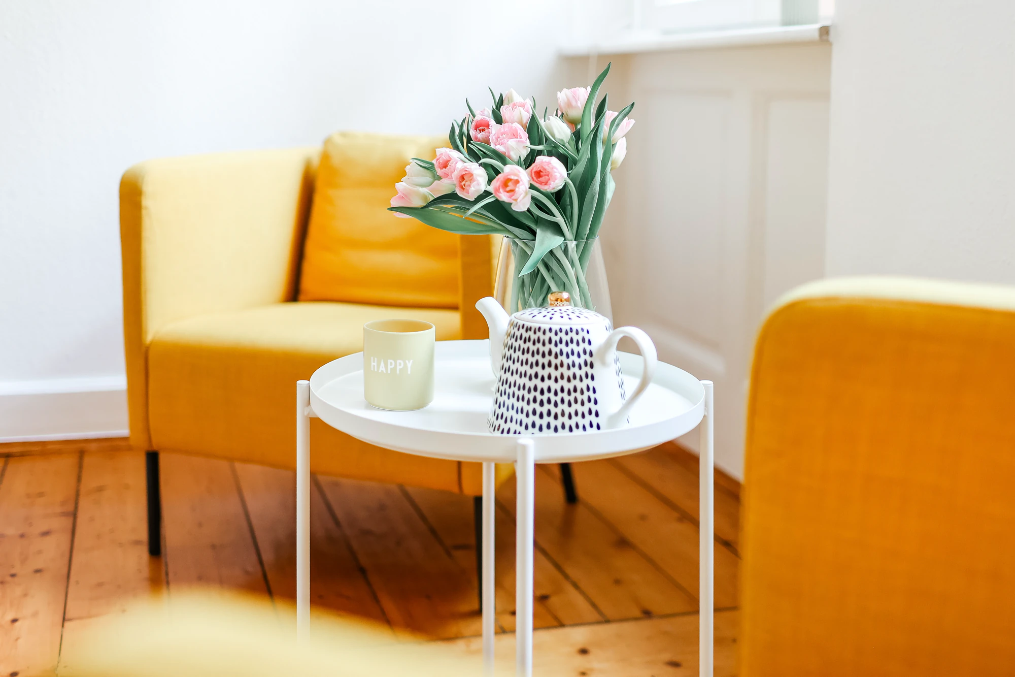 Gelbe Sessel, Blumen und Tassen in einem freundlich eingerichteten Praxisraum